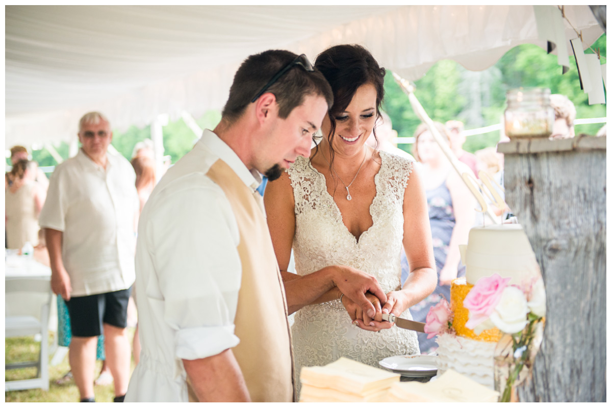 bride and groom cutting cake during farm wedding