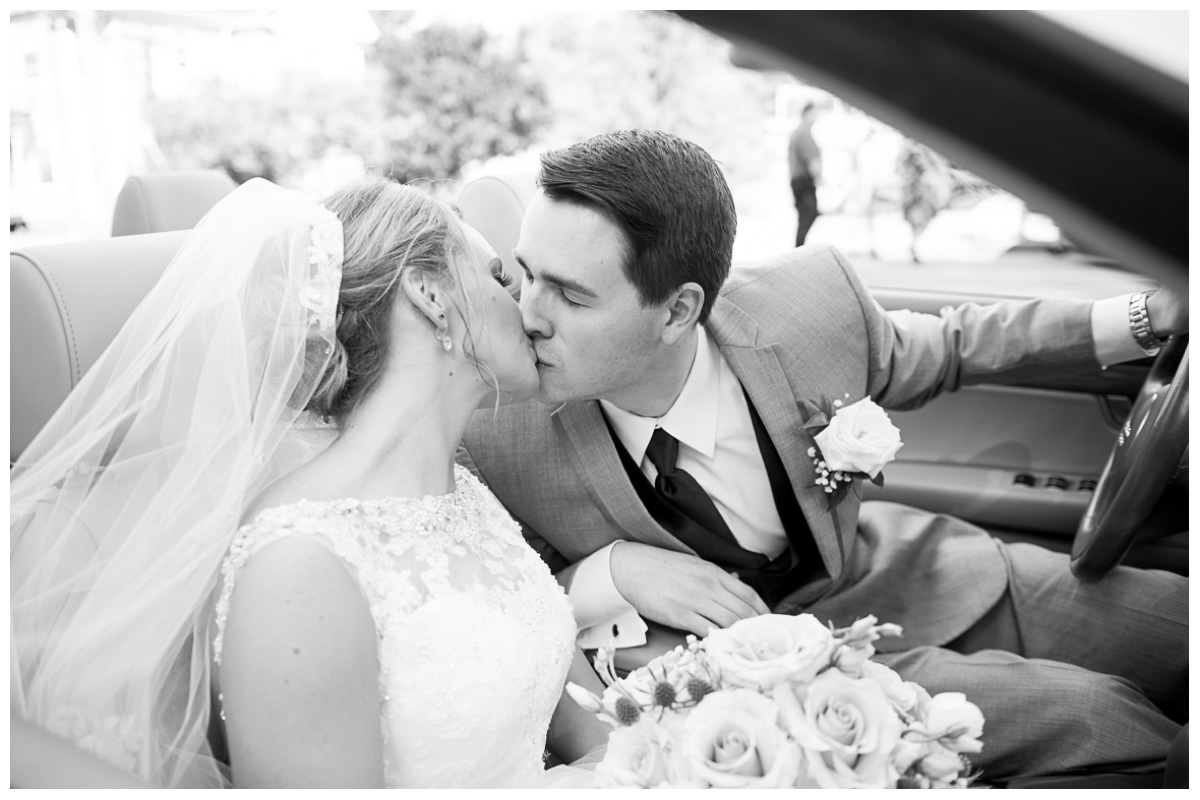 bride and groom kissing in get away car after wedding ceremony