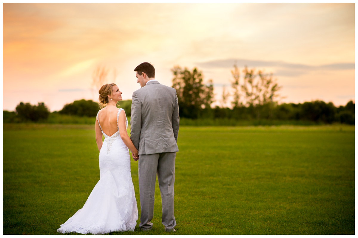 bride and groom walking hand in hand at sunset