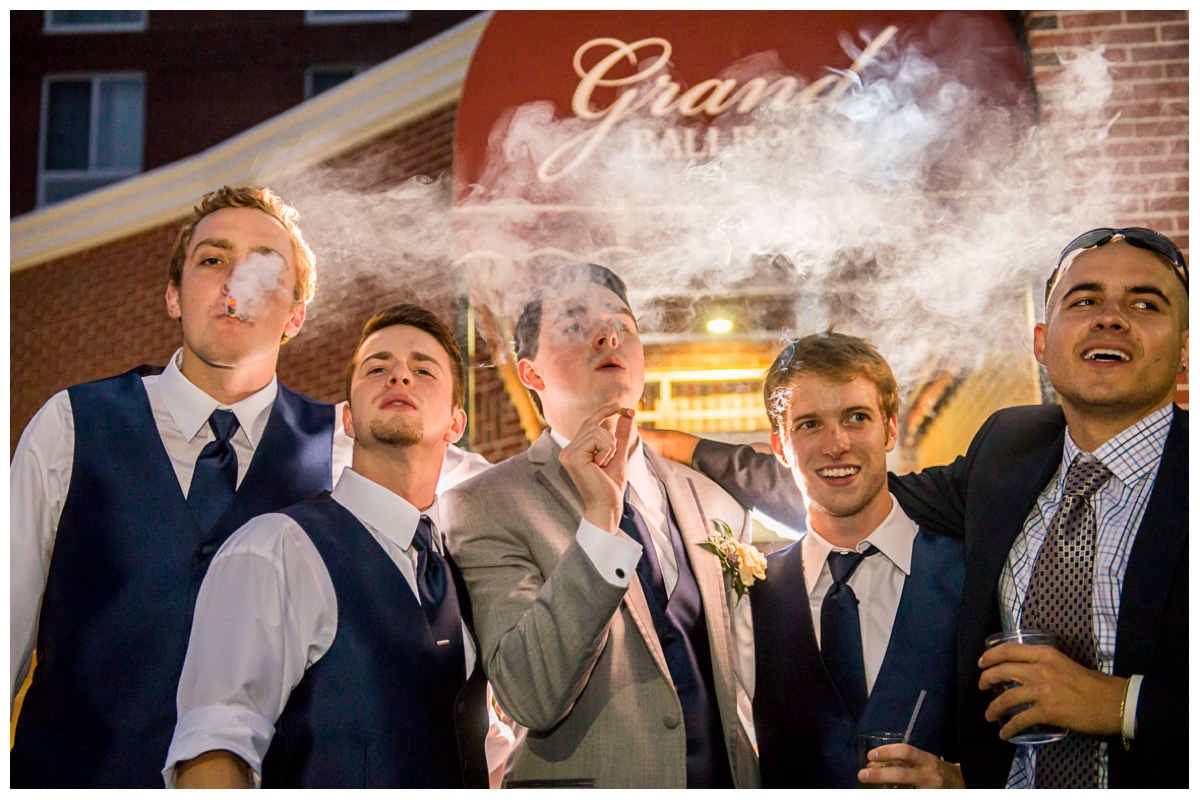 groom with groomsmen's smoking cigars at wedding reception 
