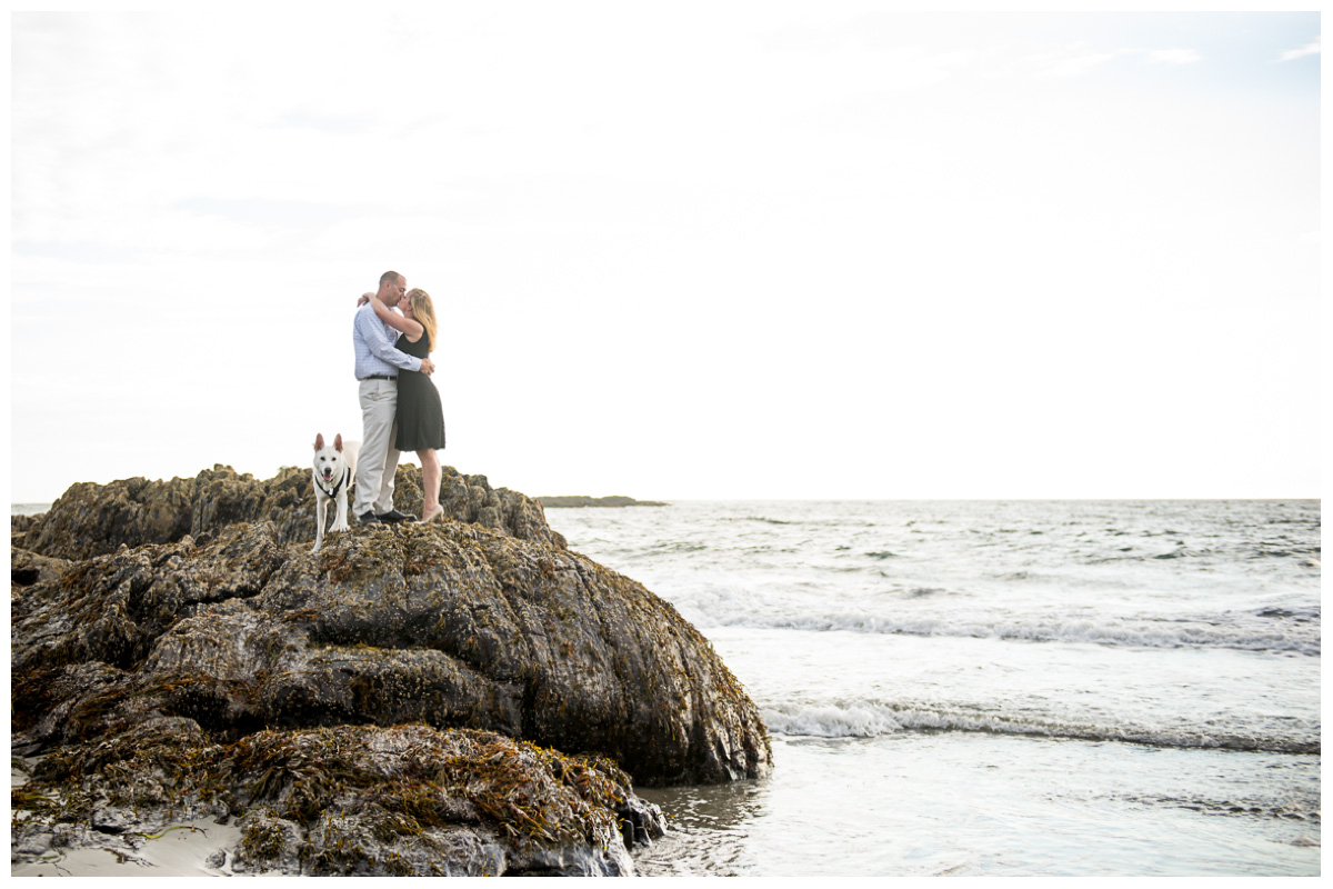 couple kissing on rock in ocean in Maine