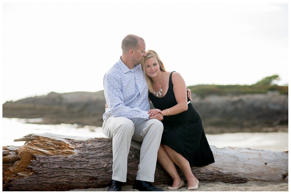 engaged couple sitting on beach at sunset