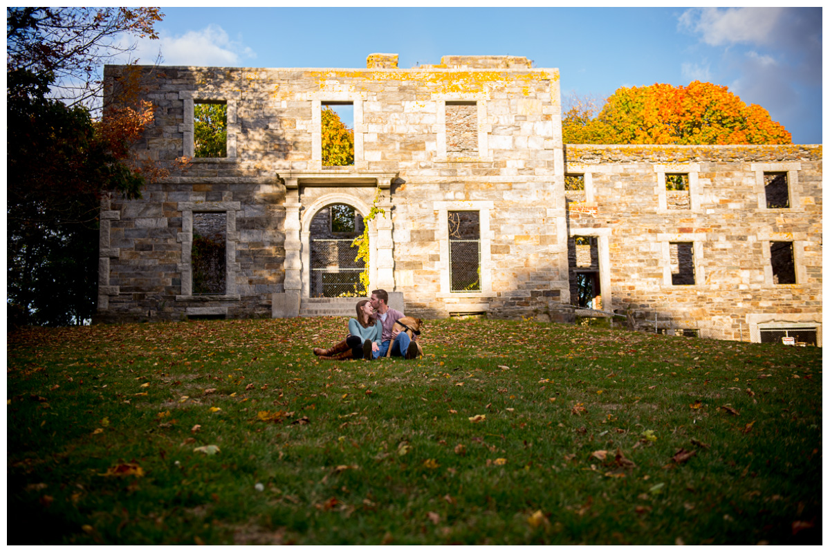 couple sitting in front of stone home in cape elizabeth for engagement photos