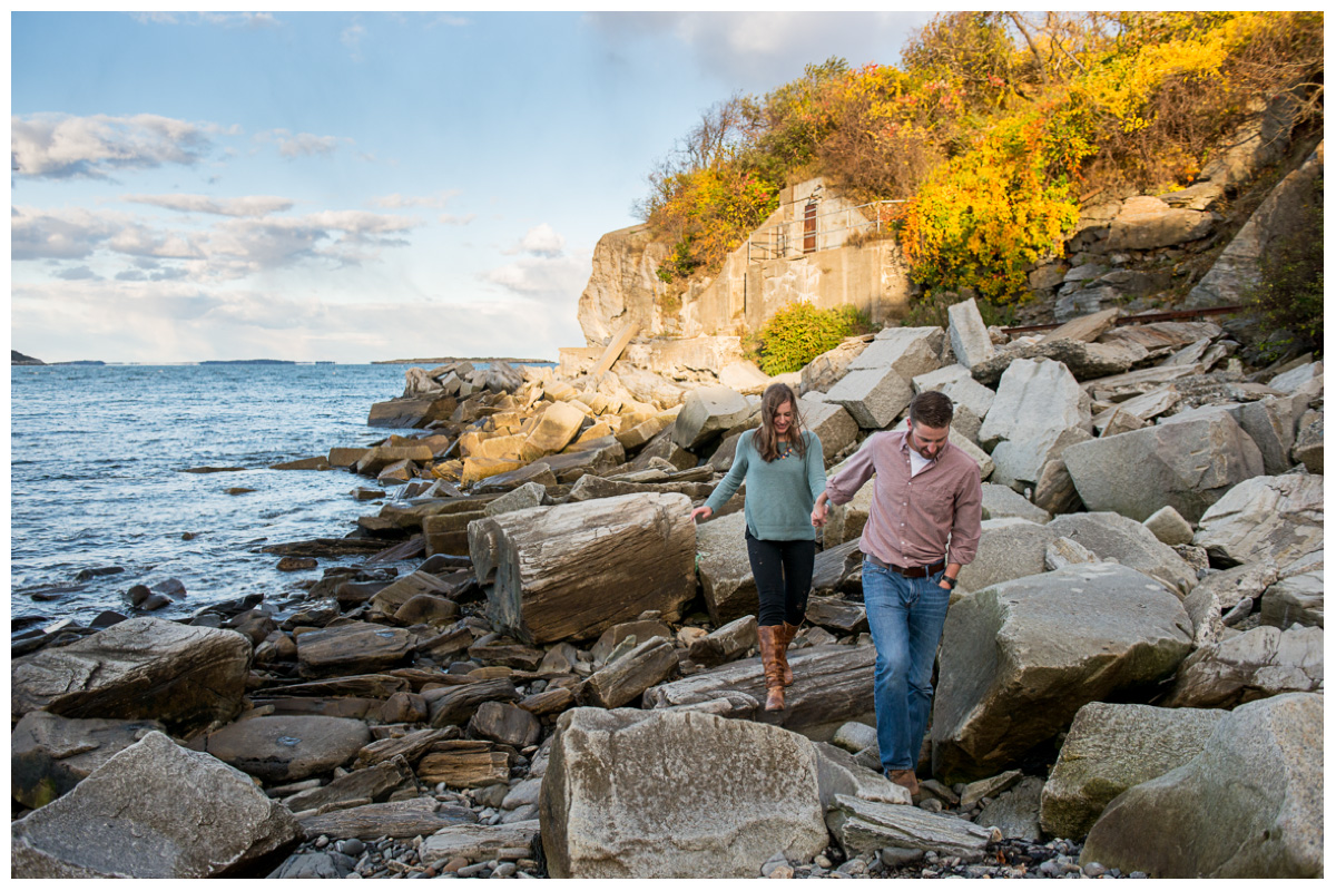 excited couple walking on the rock beach at Fort Williams