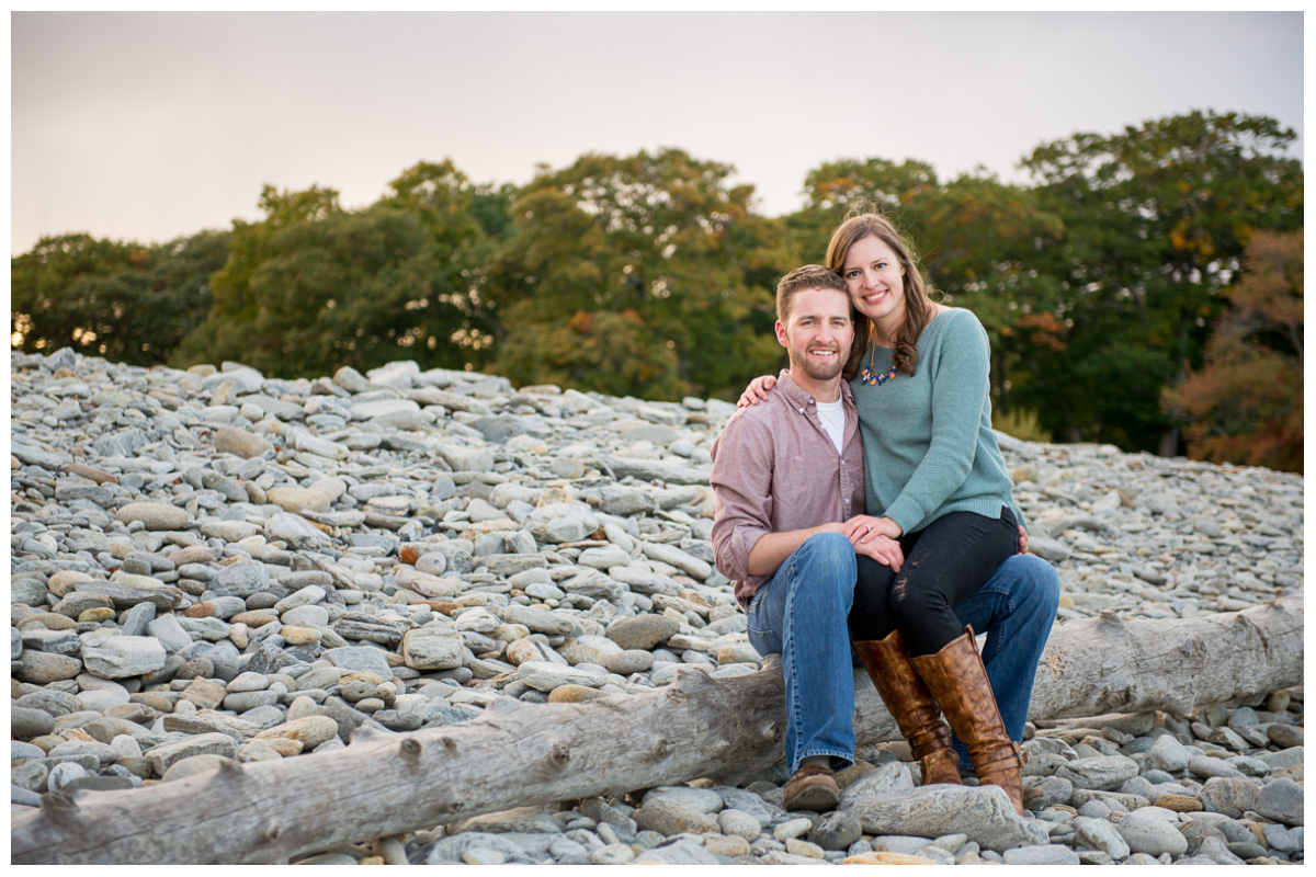 couple sitting on log on the beach for photos