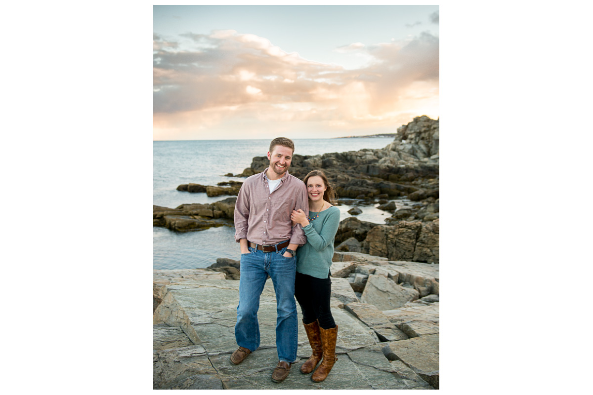 adventurous and fun couple on rocks by the ocean at Fort Williams