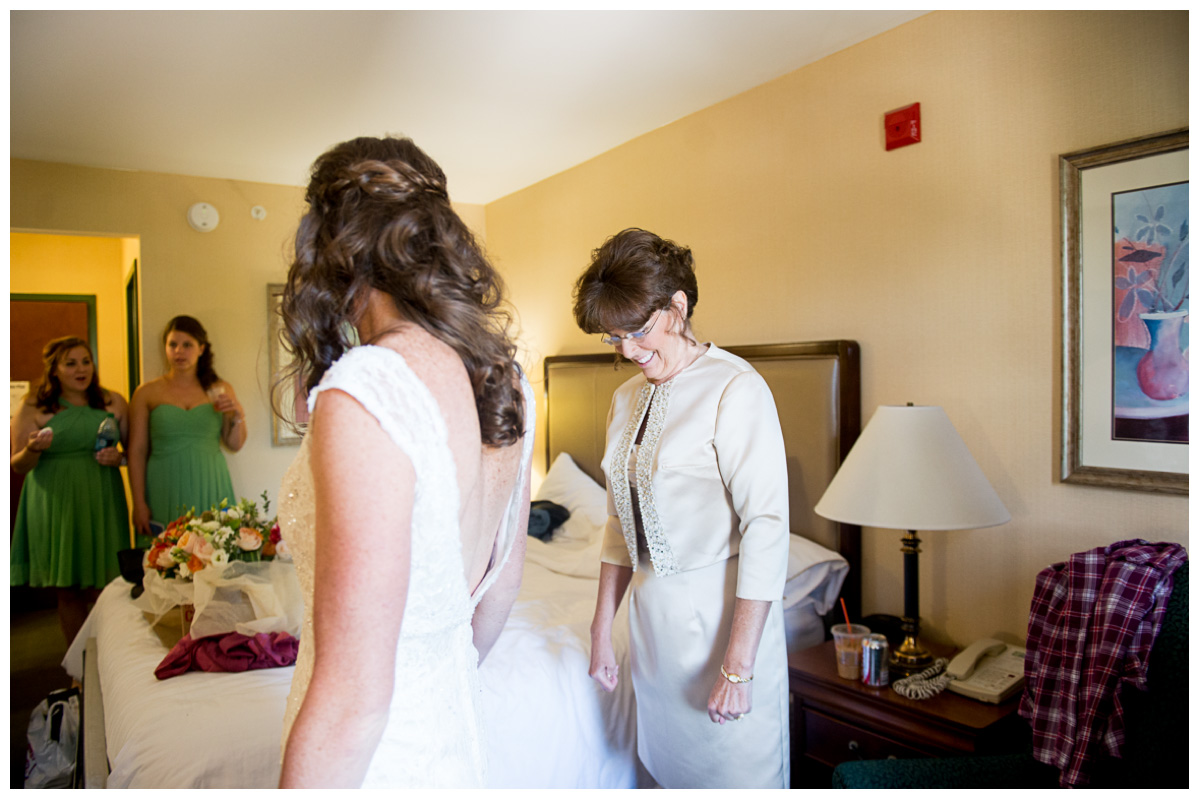 mom helping daughter into wedding dress 