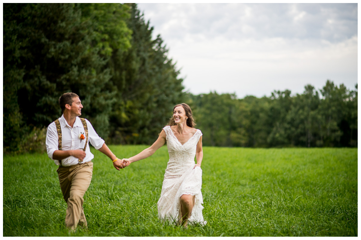 Excited couple running through green field at sunset