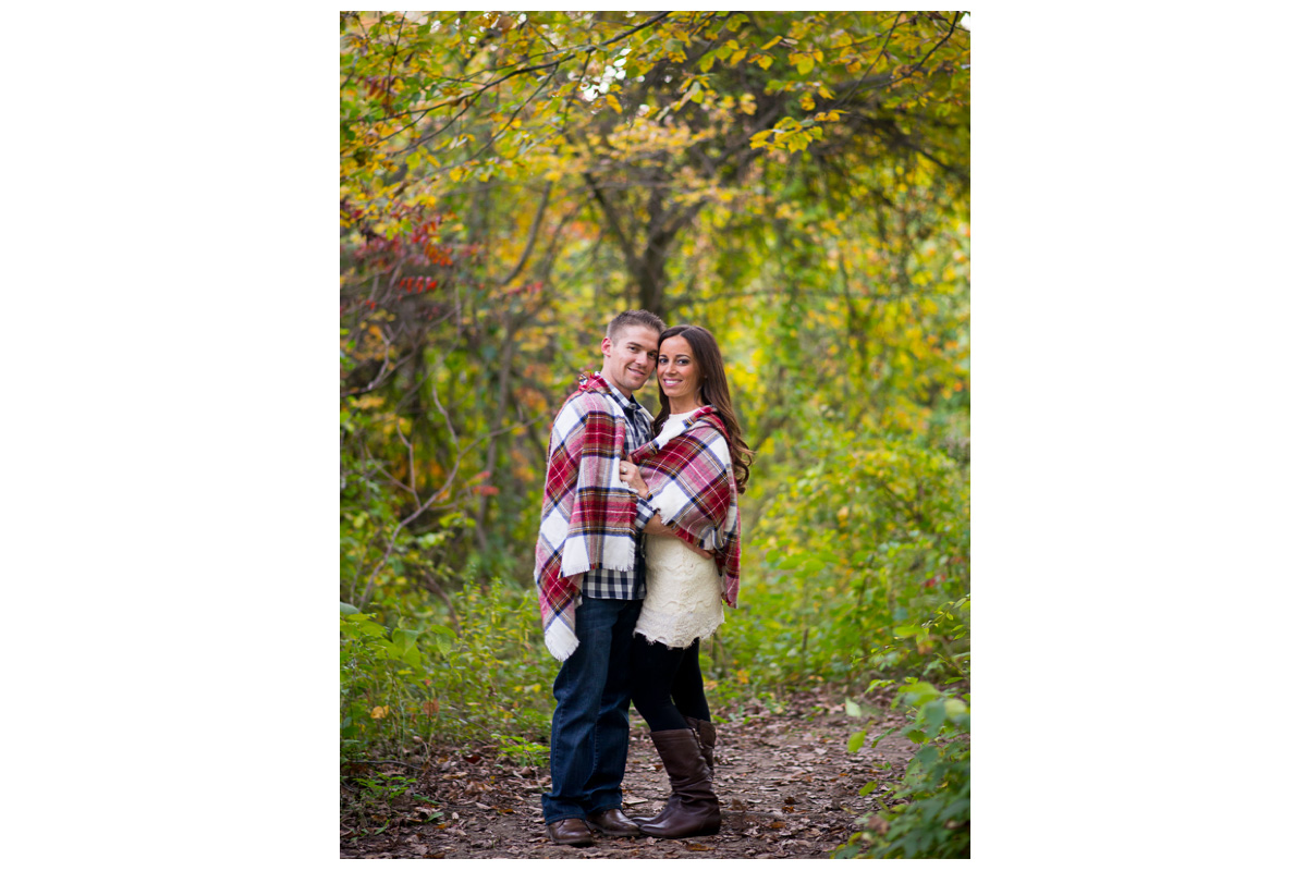 adventurous couple with blanket in the woods during fall 