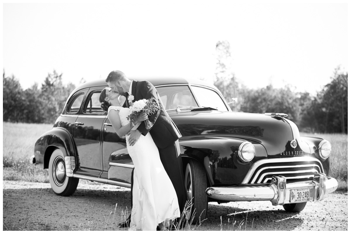 elegant couple kissing in front of antique car