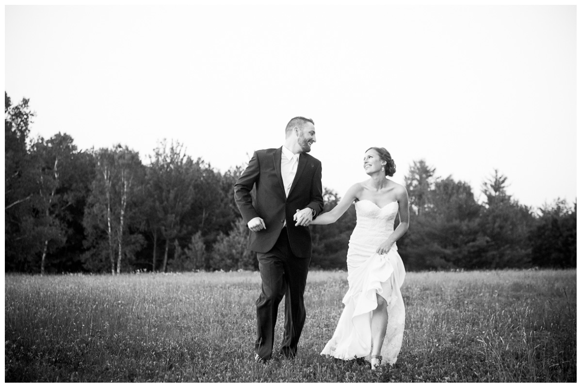 Adventurous couple running through a field in Maine during sunset