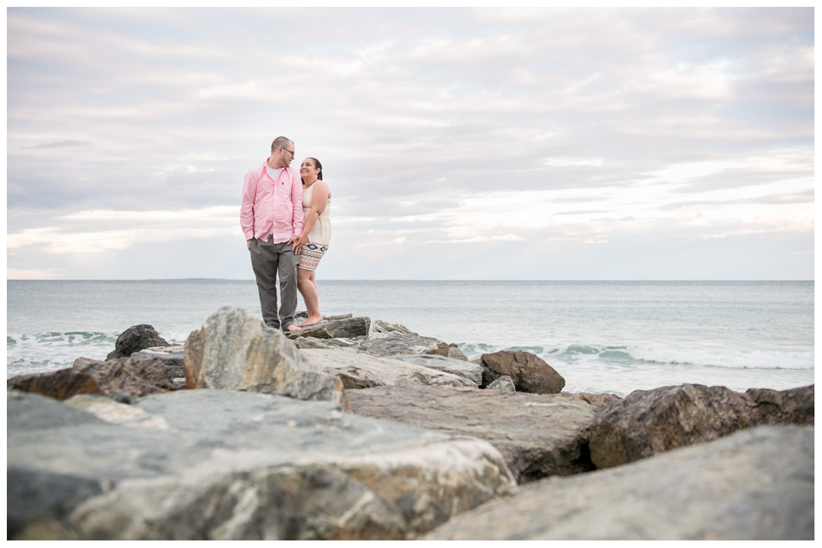 Couple standing on rocks at Wallis beach at sunset