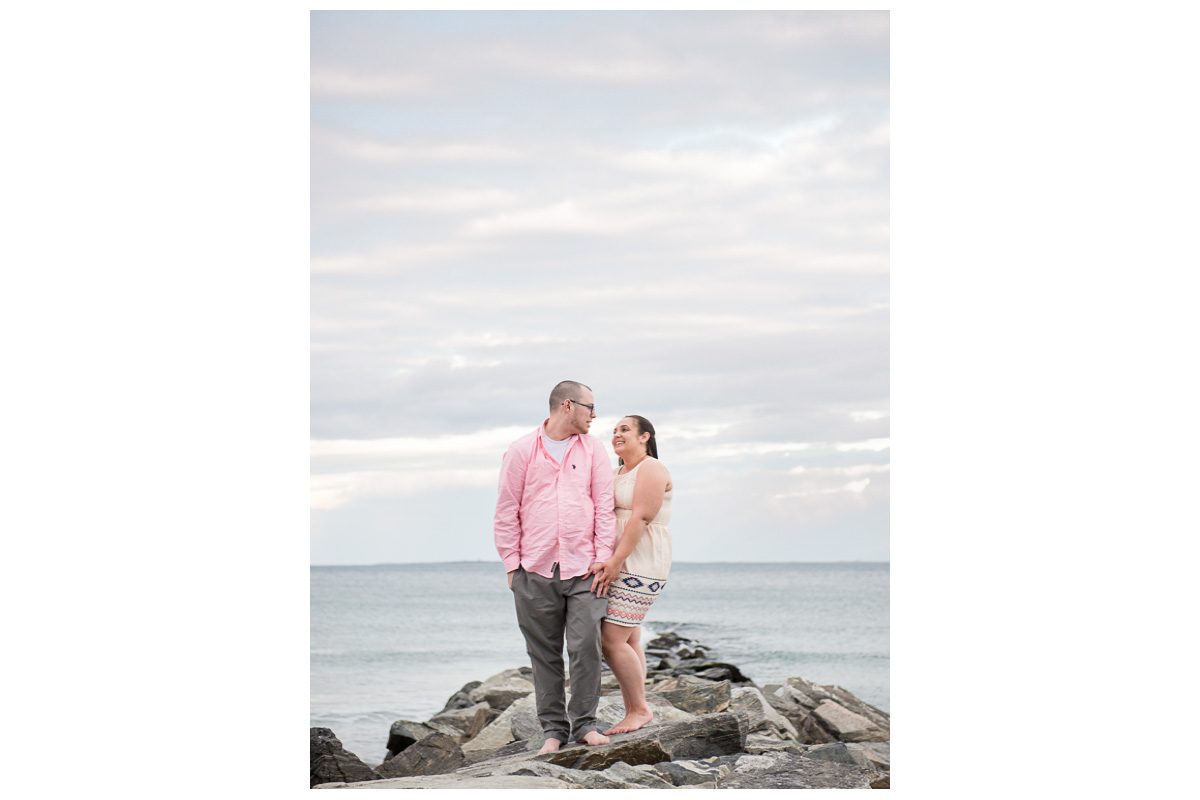 couple standing on rocks looking at each other on Rye Beach