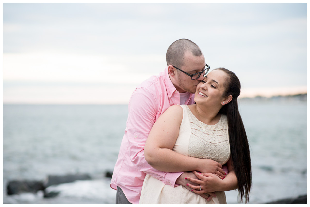 happy couple kissing next to ocean in New Hampshire