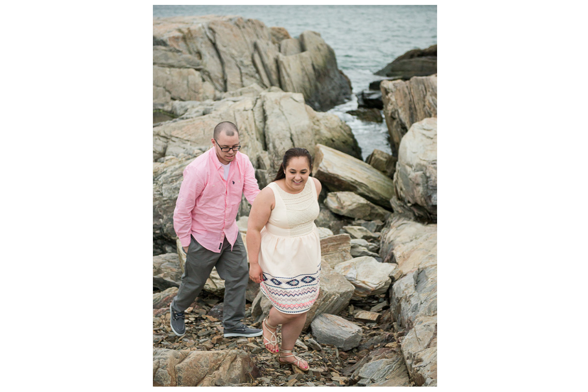 couple walking on rocks at the beach during for engagement photos