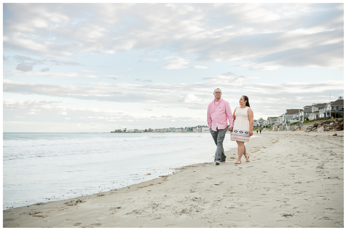 fun couple walking on Rye Beach for engagement photos at sunset