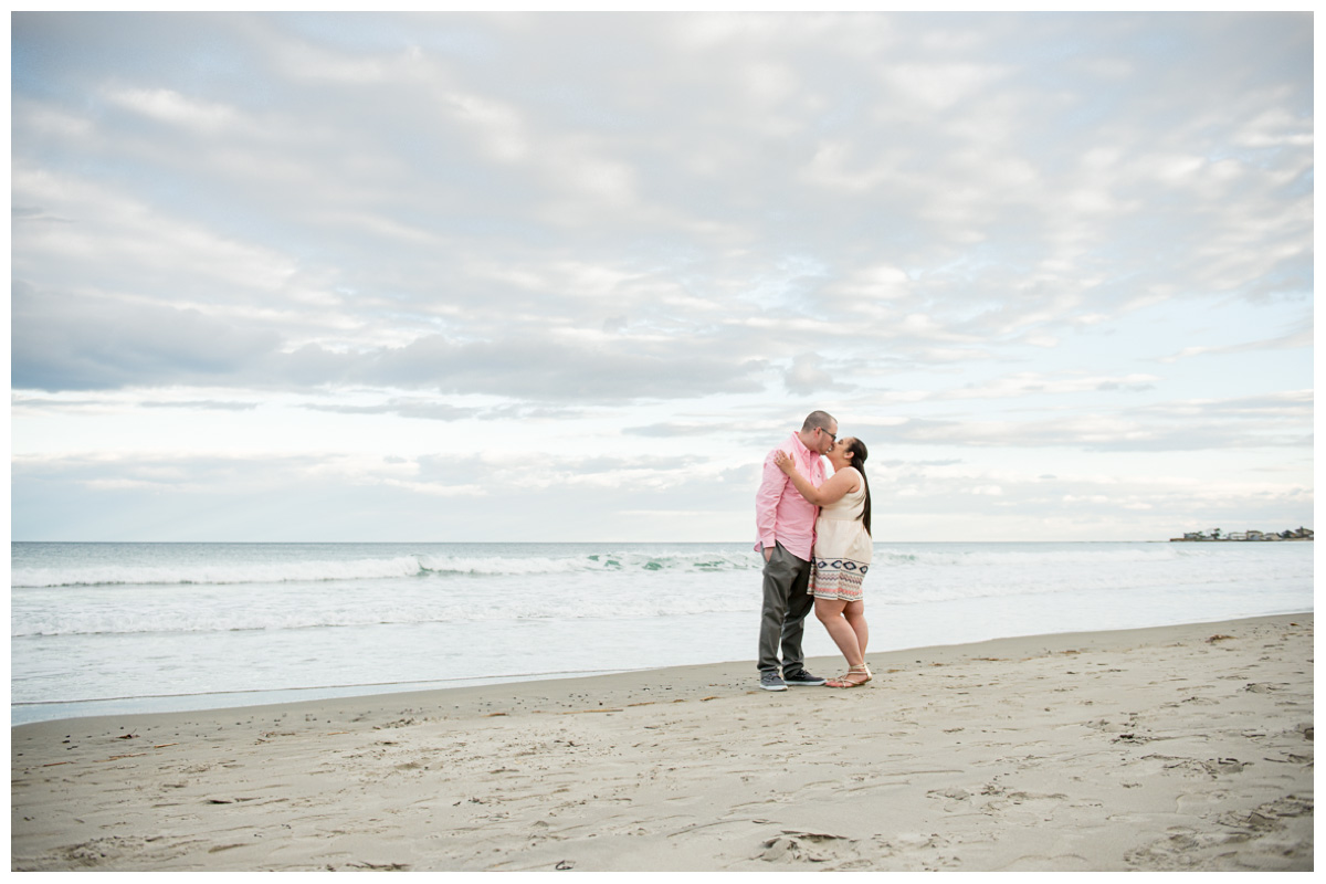 adventurous couple kissing at sunset on Rye Beach in New Hampshire