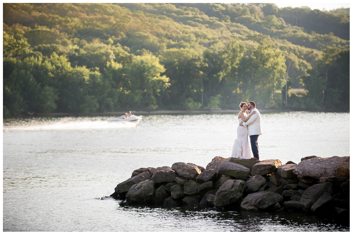 bride and groom on rocks in connecticut river 