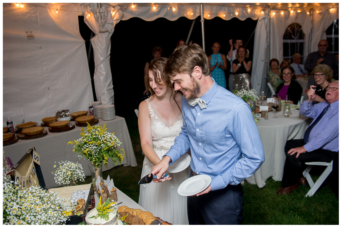couple cutting the cake inside a tent