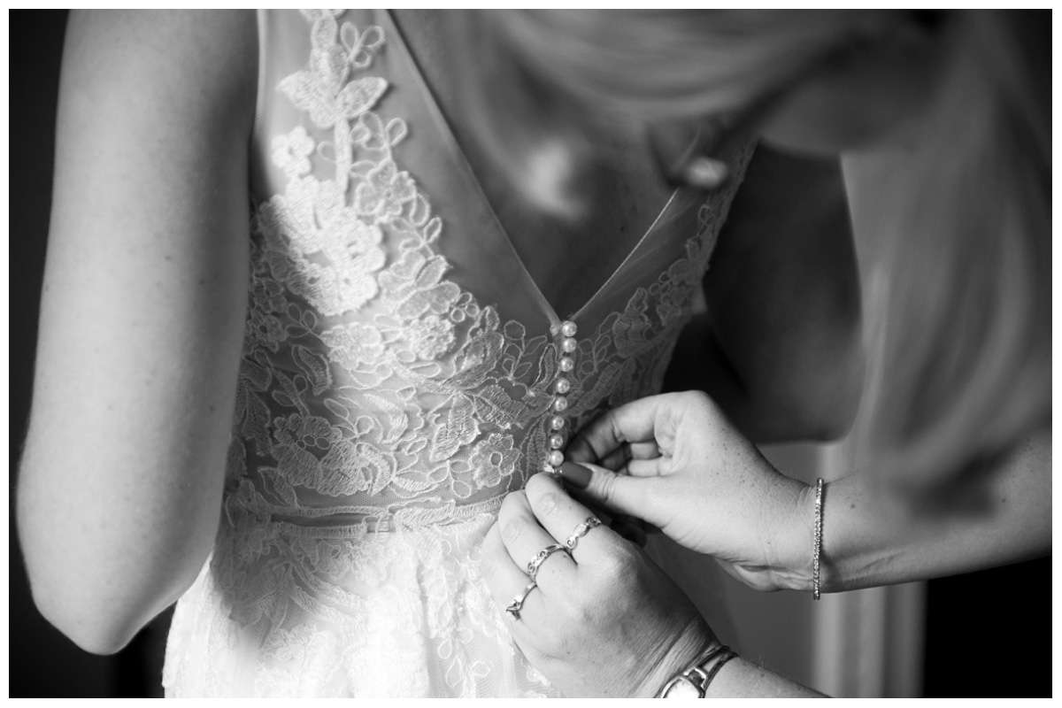 Best friends dressing bride in black and white with lace wedding gown