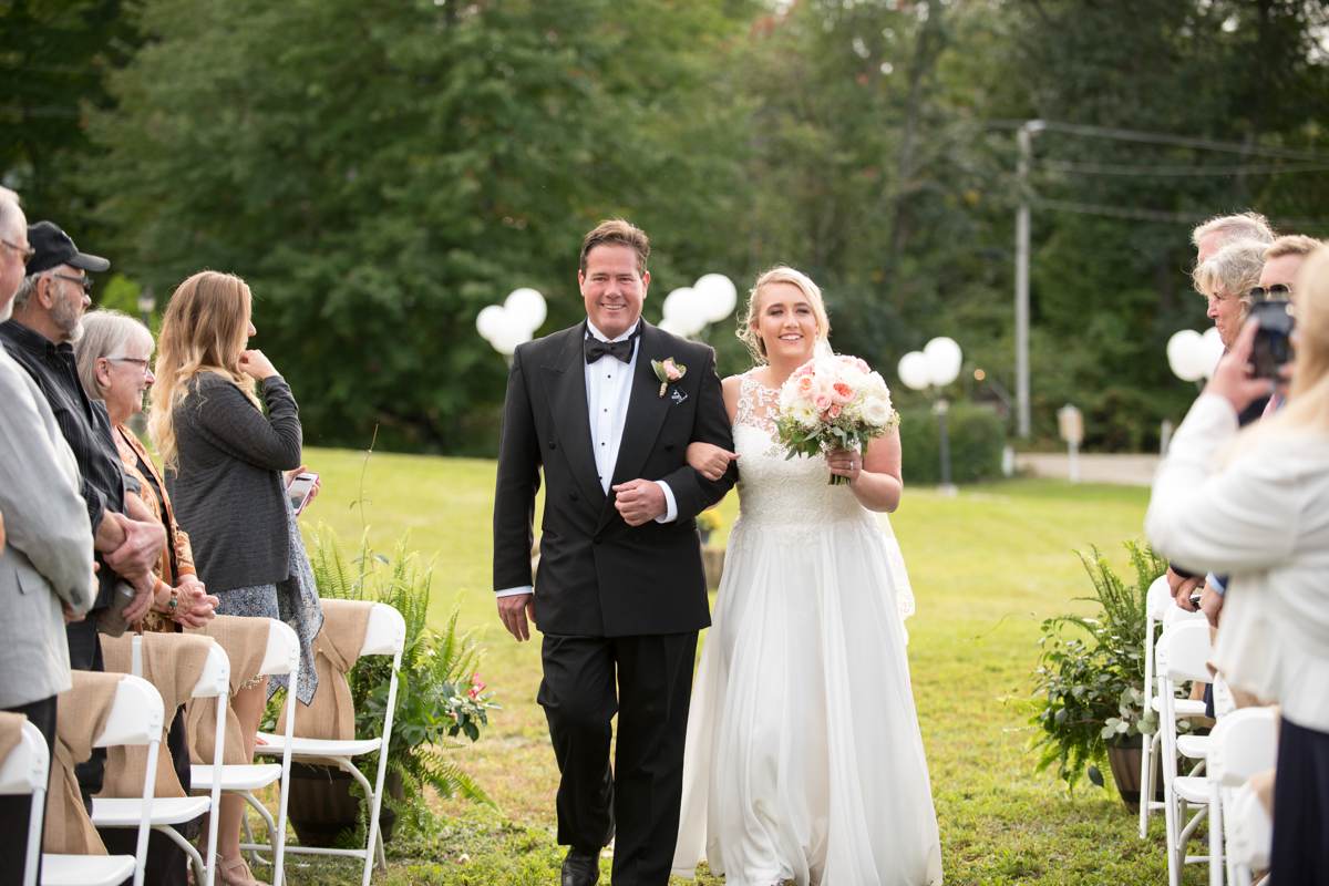 bride with dad walking down the aisle at rustic outdoor wedding in new hampshire