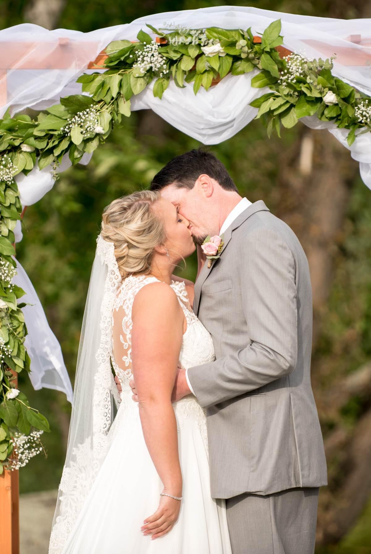 couple kissing under arbor, rustic outside wedding in new hampshire